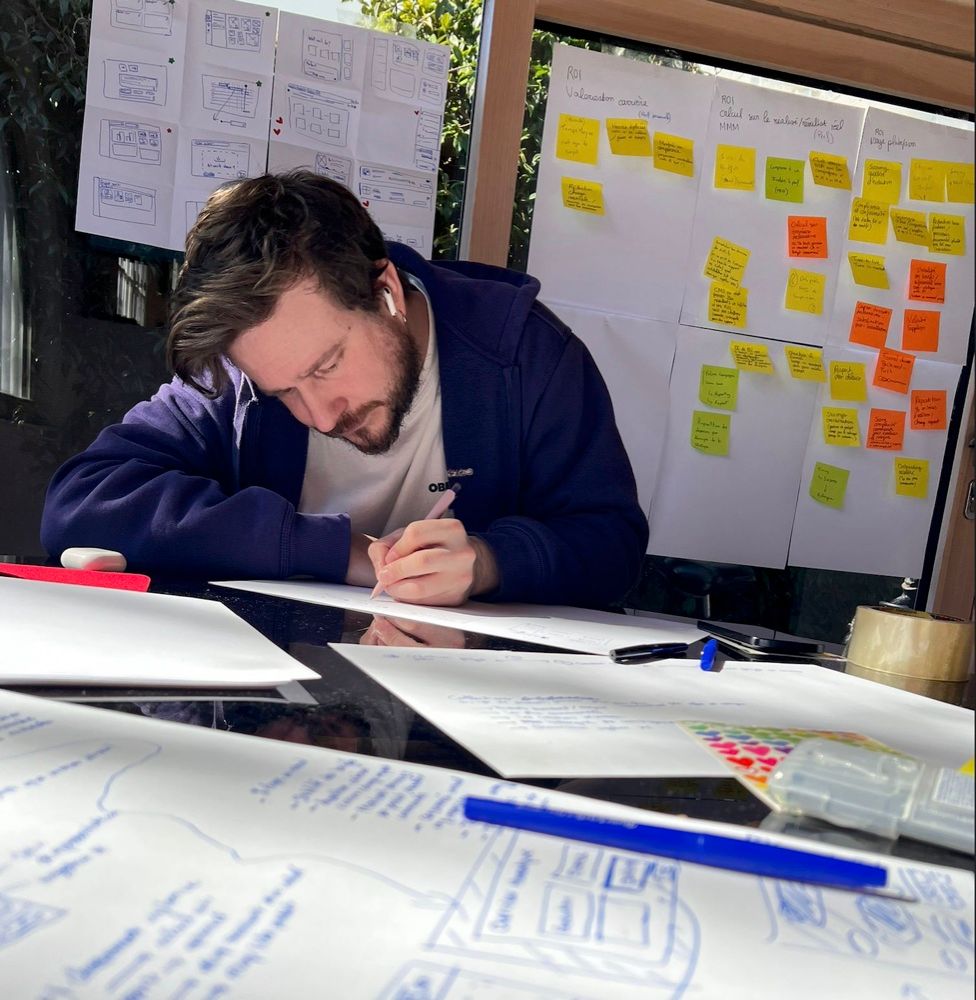Frédéric Oglaza dessine des wireframes à la main, devant un mur de post-it