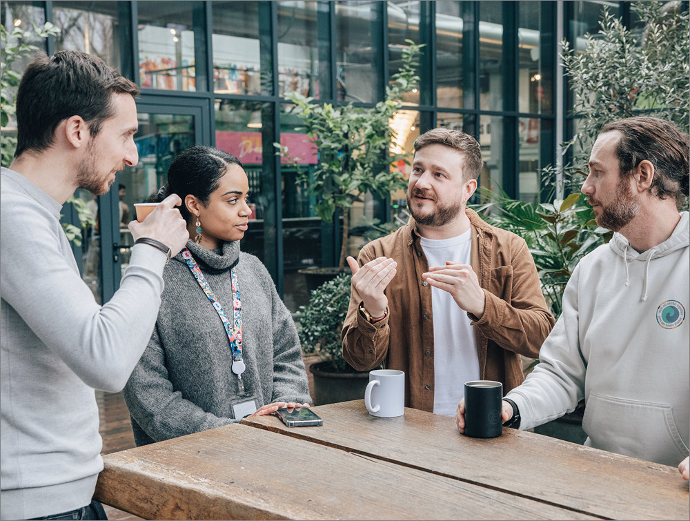 Quatre membres d'une équipe produit en discussion autour d'un café